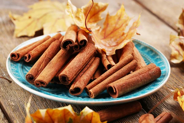 Ahşap zemin üzerine sarı yaprakları ile plaka üzerine tarçın sopa