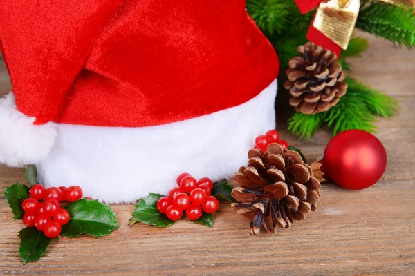 Leaves of mistletoe with Christmas hat on table close-up — Stock Photo, Image