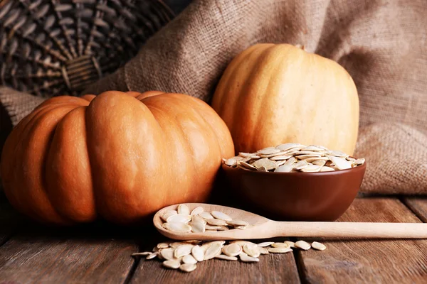 Pumpkins and seeds on wooden background — Stock Photo, Image
