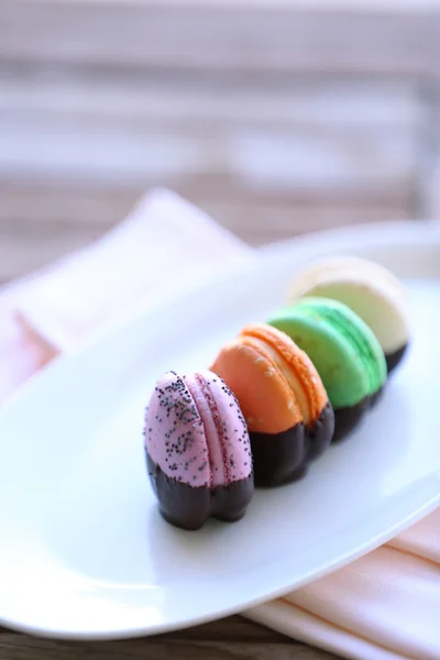 Macaroons coloridos na placa na mesa de madeira, close-up — Fotografia de Stock