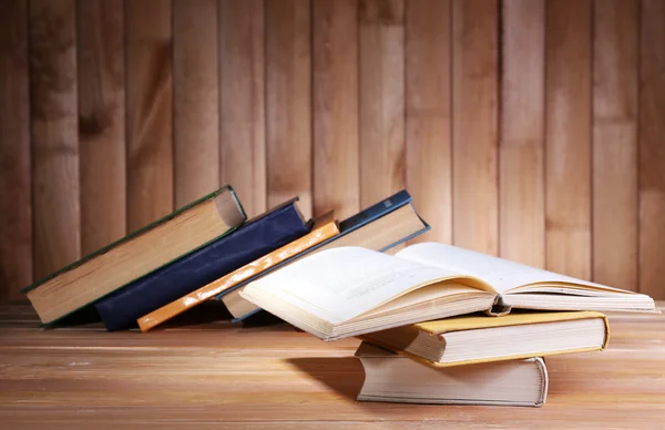 Libros sobre mesa de madera sobre fondo de pared de madera — Foto de Stock