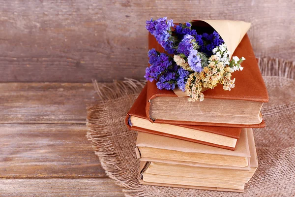 Libros y flores silvestres en servilleta sobre mesa de madera sobre fondo de pared de madera — Foto de Stock