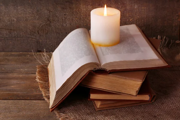 Книги и свечи на салфетке на деревянном столе на фоне деревянной стены — стоковое фото