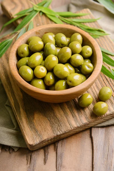 Olive verdi in ciotola con foglie in tavola primo piano — Foto Stock