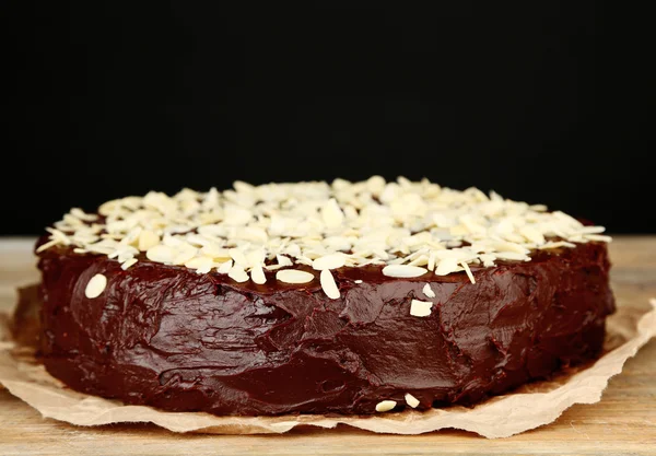 Leckere Schokoladenkuchen mit Mandeln, auf Holztisch, auf dunklem Hintergrund — Stockfoto