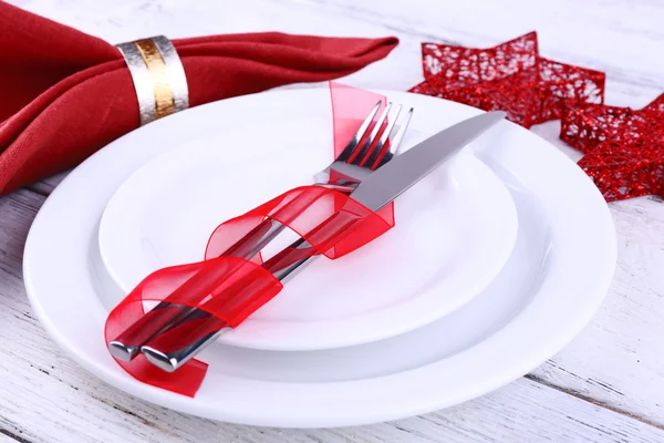 Placas brancas, faca, garfo, guardanapo e decoração de Natal em fundo de madeira — Fotografia de Stock