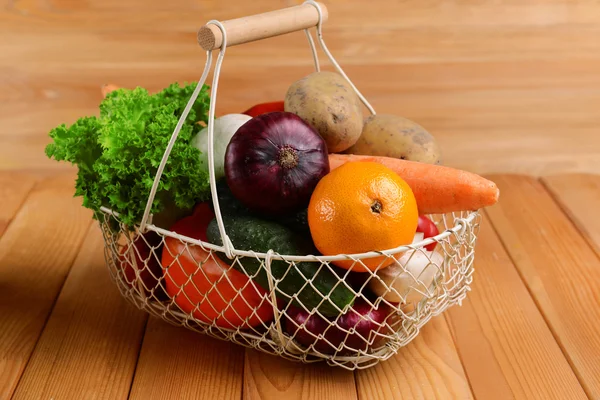 Fresh organic fruits and vegetables in wicker basket on wooden background