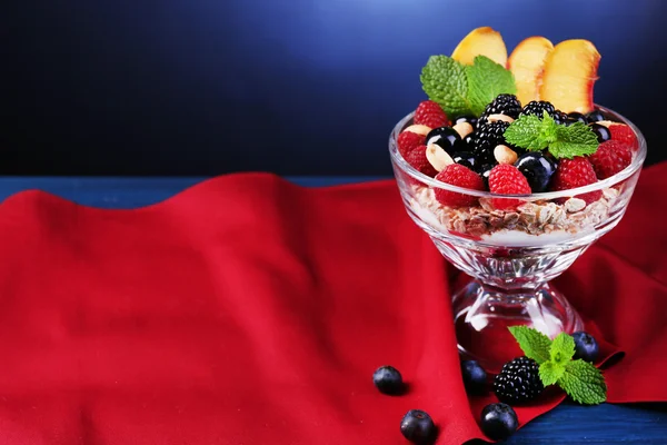 Hälsosam frukost - yoghurt med färsk frukt, bär och müsli serveras i glasskål på färg träbord, på mörka bakgrund — Stockfoto
