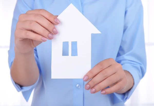 Woman hands holding paper house on light background — Stock Photo, Image