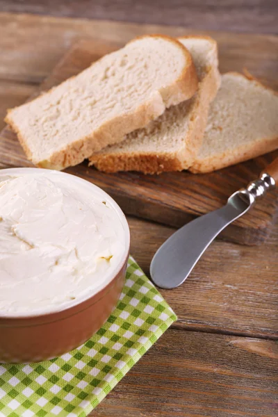 Fresh homemade butter in bowl and sliced bread, on wooden background — Stock Photo, Image