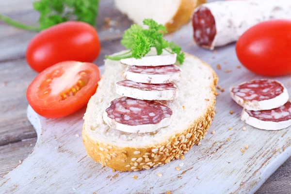 Fransk salami med tomater, persilja och bröd på skärbräda på trä bakgrund — Stockfoto