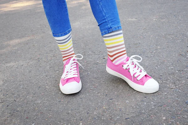 Female legs in colorful socks and sneakers outdoors — Stock Photo, Image