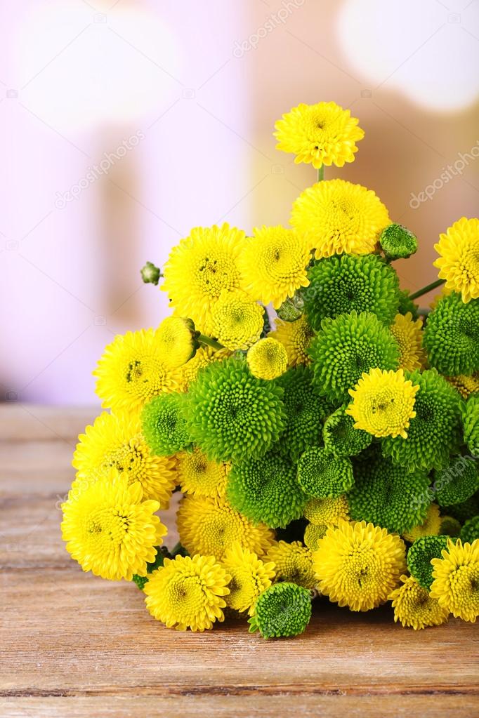 Beautiful bouquet of chrysanthemums flowers on wooden table, on light background