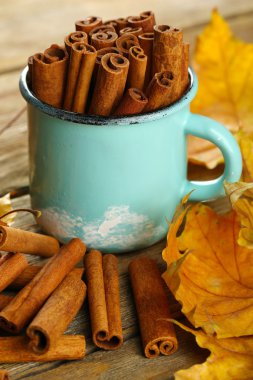 Ahşap zemin üzerine sarı yaprakları ile bardağa tarçın sopa