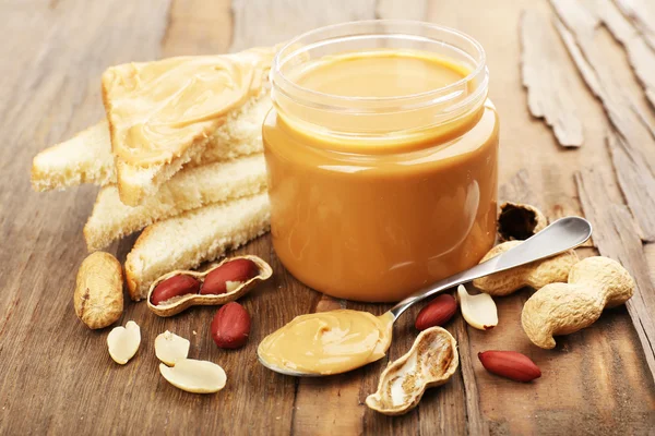 Cremige Erdnussbutter im Glas, auf Holztisch — Stockfoto