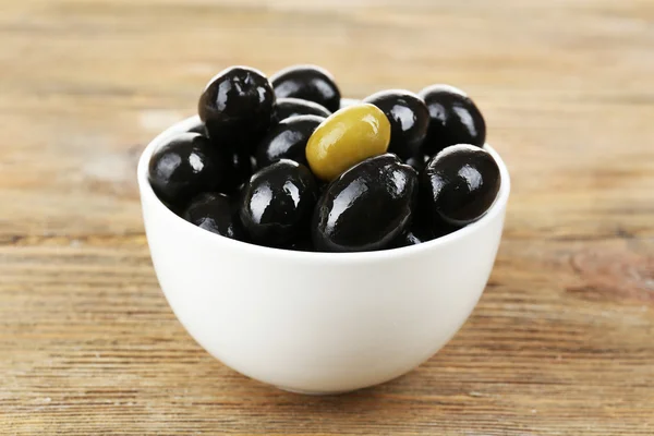 Individuality concept. Olive in bowl on wooden table — Stock Photo, Image