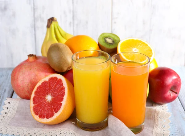Frukt- och Grönsaksjuice och färsk frukt på servett på träbord på trävägg bakgrund — Stockfoto