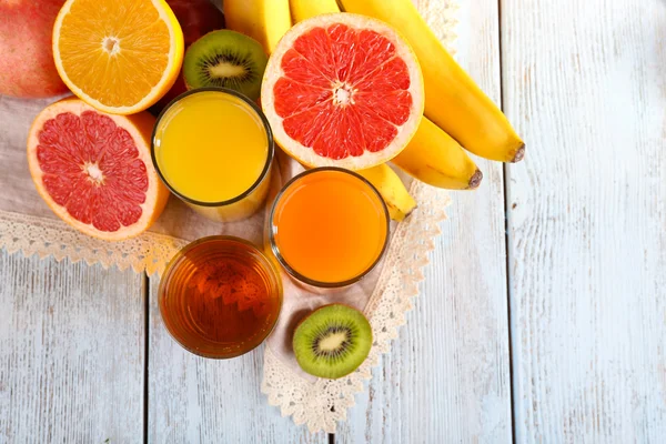 Fruit and vegetable juice and fresh fruits on napkin on wooden background — Stock Photo, Image