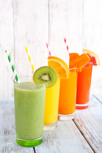Groenten en fruit sap in glazen en stukken van vers fruit op houten tafel op houten muur achtergrond — Stockfoto
