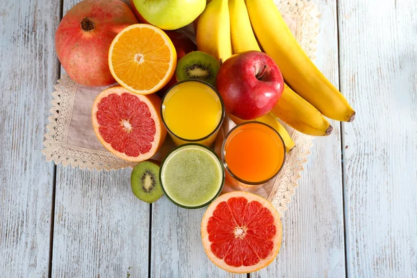 Suco de frutas e vegetais e frutas frescas em guardanapo em fundo de madeira — Fotografia de Stock