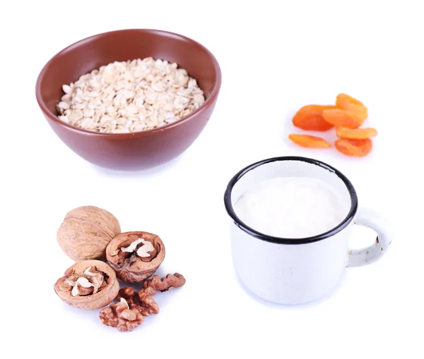 Bowl of oatmeal, mug of milk, dried apricots and walnuts isolated on white — Stock Photo, Image