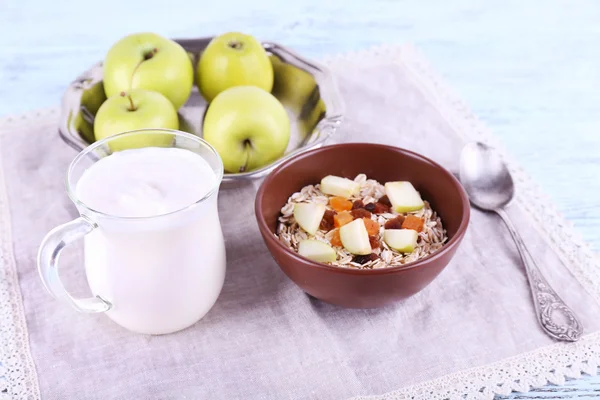 Cuenco de avena, albaricoques secos, manzanas y yogur sobre servilleta sobre fondo de madera azul —  Fotos de Stock