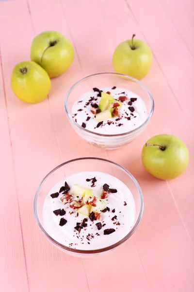 Вівсянка з йогуртом у мисці, яблука та волоські горіхи на рожевому дерев'яному фоні — стокове фото