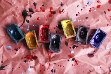 Suluboya boya küpleri ve kahverengi kağıt arka plan üzerine dökülen boya