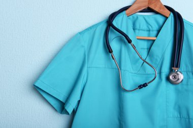 Askı üzerinde mavi arka plan üzerinde stetoskop ile doktor gömlek