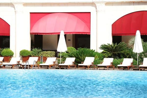 Lounge sunbeds near swimming pool — Stock Photo, Image