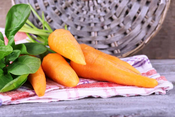 Carrots and sorrel on napkin on cutting board on wooden table — Stock Photo, Image