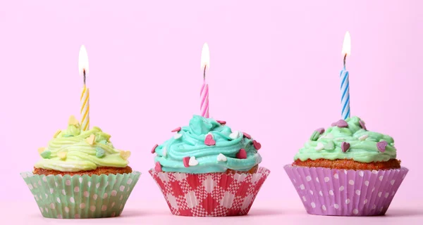 Deliciosos cupcakes de cumpleaños en la mesa sobre fondo rosa — Foto de Stock
