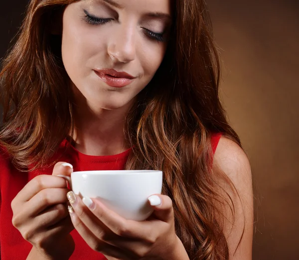 Hermosa joven con taza de café sobre fondo marrón —  Fotos de Stock