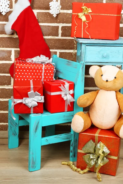 Regalos de Navidad en silla y librería sobre fondo de pared de ladrillo marrón — Foto de Stock