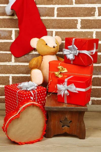 Christmas presents on stool on brown brick wall background — Stock Photo, Image