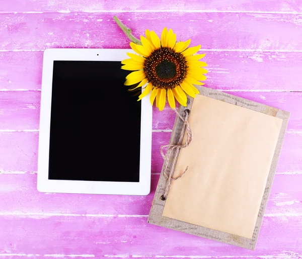 Tablet, notebook e girassol sobre fundo de madeira — Fotografia de Stock
