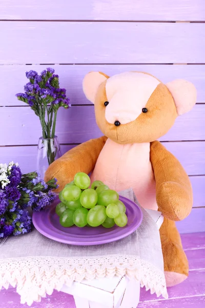 Игрушечный медведь и виноград на деревянном фоне — стоковое фото