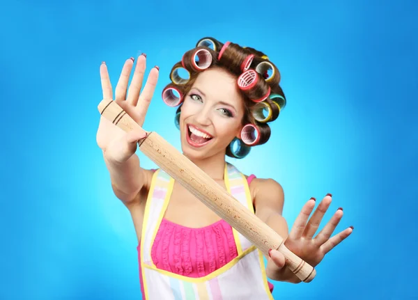Menina bonita em encrespadores de cabelo no fundo azul — Fotografia de Stock