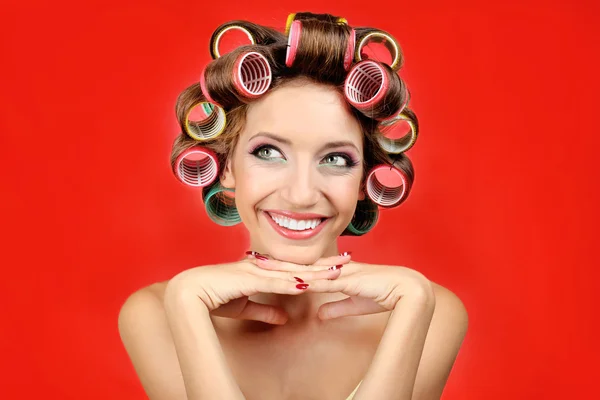 Krásná dívka v natáčky na vlasy na červeném pozadí — Stock fotografie