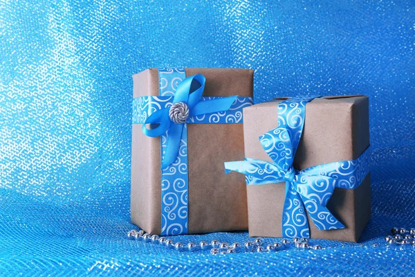 Holiday gift boxes decorated with blue ribbon on blue fabric background — Stock Photo, Image