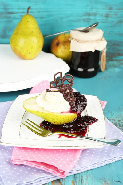 Lekker dessert met peer, crème en berry saus op plaat, op een houten achtergrond kleur — Stockfoto