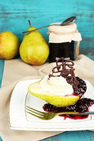 Lekker dessert met peer, crème en berry saus op plaat, op een houten achtergrond kleur — Stockfoto