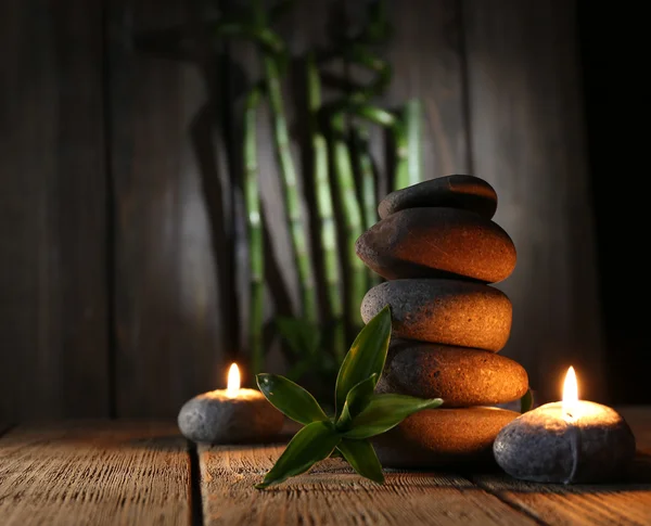 Курортные камни, свечи на деревянном столе на темном фоне — стоковое фото