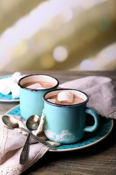 Tassen mit schmackhaftem heißem Kakao, auf Holztisch, auf hellem Hintergrund — Stockfoto