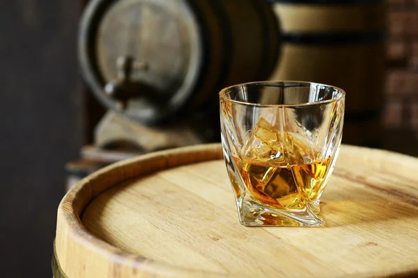 Glass of brandy in cellar with old barrels — Stock Photo, Image