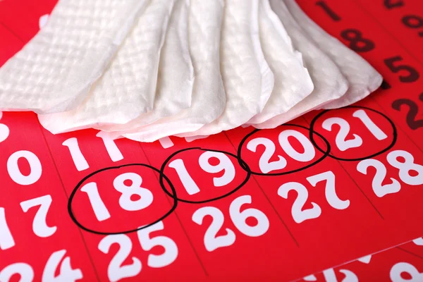 Coussinets sanitaires sur fond de calendrier rouge — Photo