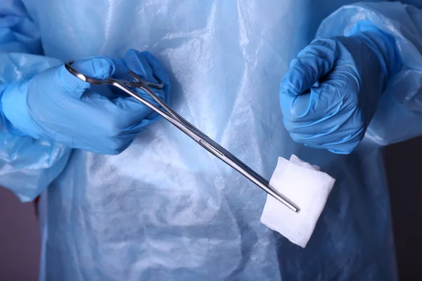 Руки хирурга держат зажим с салфеткой крупным планом — стоковое фото