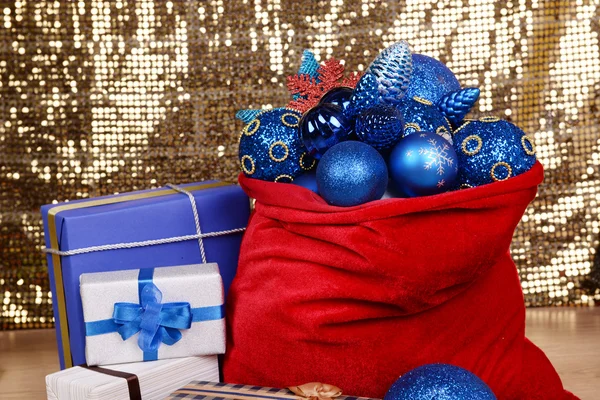 Rote Tasche mit Weihnachtsspielzeug und Geschenken auf Stoffhintergrund — Stockfoto