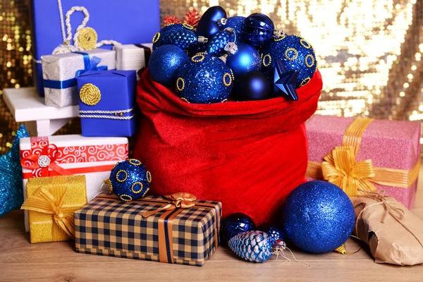 Noel oyuncaklar ve hediyeler kumaş arka plan üzerinde kırmızı çanta — Stok fotoğraf