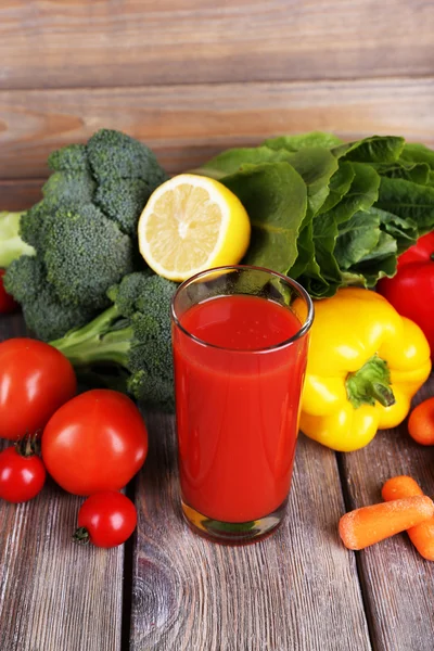 Jus de tomate en verre et légumes frais sur table en bois sur fond mural en bois — Photo